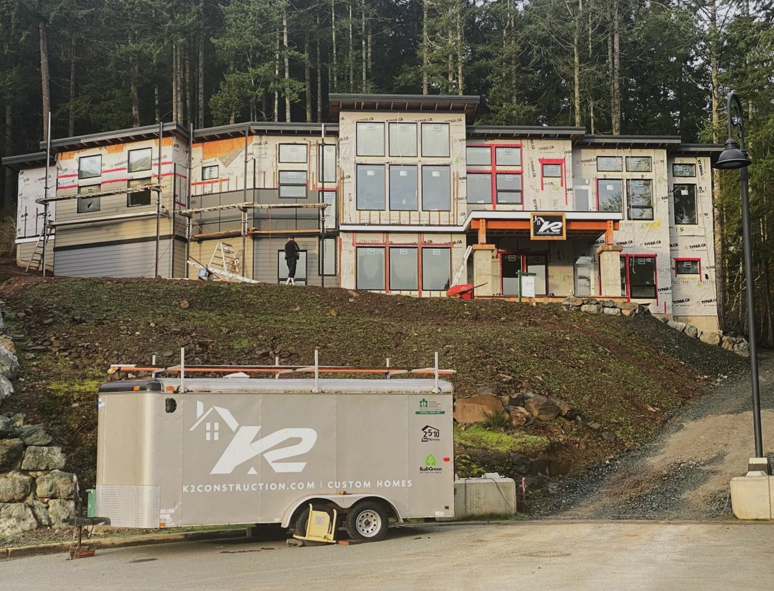 branded K2 trailer sitting in front of custom home under construction